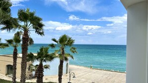 Blick auf die Küste mit Palmen, einem Strand und einem Gebäude mit Balkon.