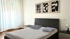 A bedroom with a bed, bedside tables, and abstract wall art. - A39 - Ancona, comfortable three-room apartment in the historic center (Ancona)
