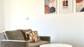 A living room with a grey sofa, a patterned throw pillow, a round white table, and abstract art on the wall. - A39 - Ancona, comfortable three-room apartment in the historic center (Ancona)