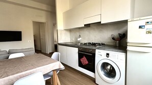 A compact kitchen with a built-in washing machine, a dining area with a table and chairs, and a modern design. - A39 - Ancona, comfortable three-room apartment in the historic center (Ancona)