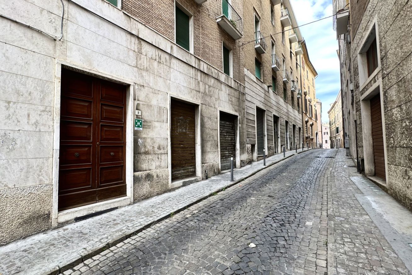 Eine enge Kopfsteinpflasterstraße, gesäumt von historischen Gebäuden mit geschlossenen Fensterläden und einem sichtbaren, grünen Schild.