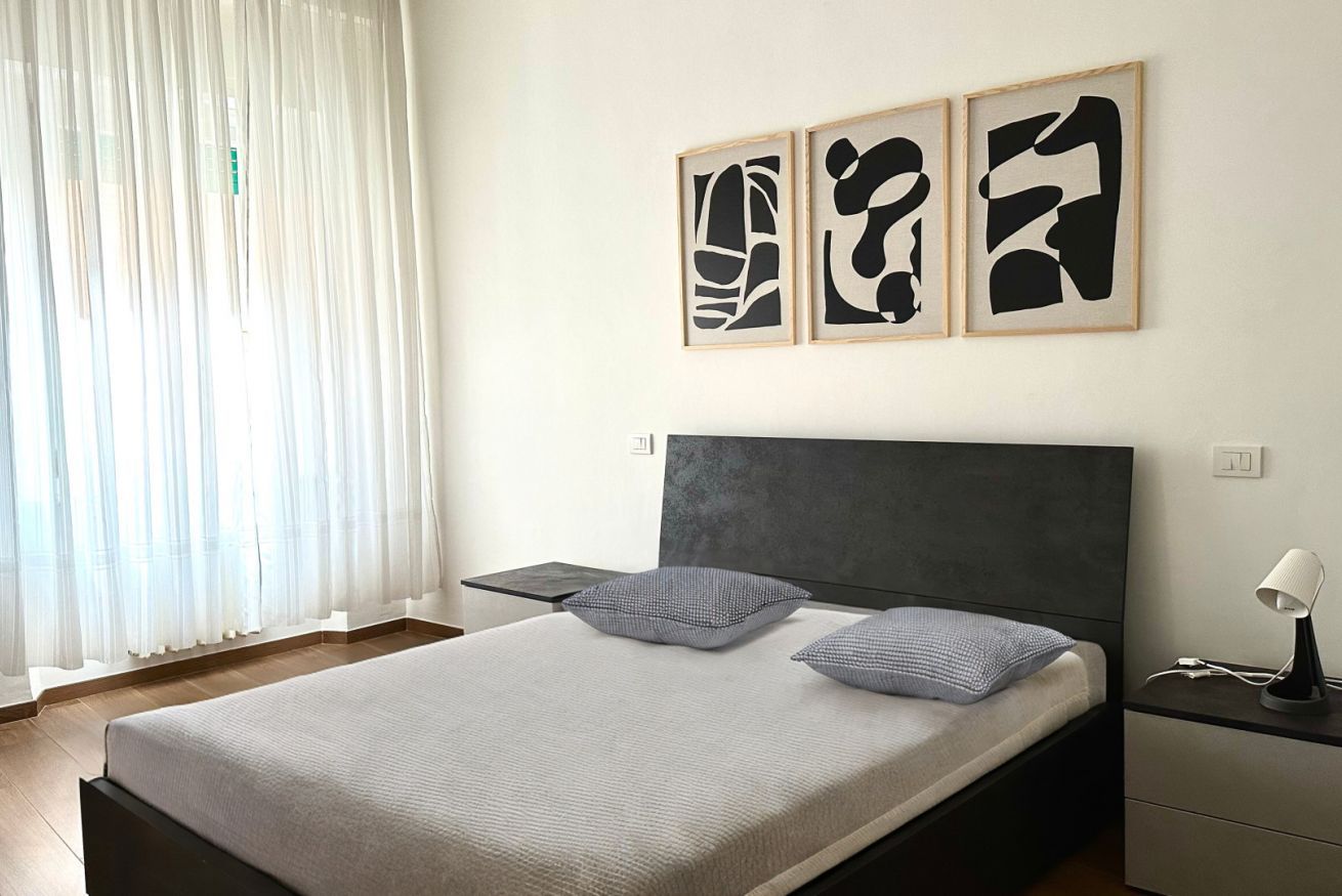 A bedroom with a bed, bedside tables, and abstract wall art.