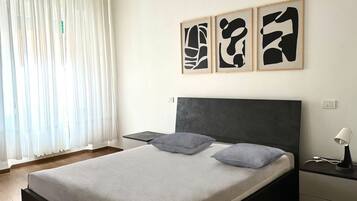 A bedroom with a bed, bedside tables, and abstract wall art.