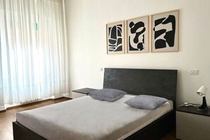 A bedroom with a bed, bedside tables, and abstract wall art.