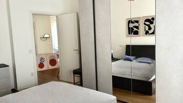 Ein Schlafzimmer mit einem Bett, einem Spiegel und einer Tür zu einem anderen Raum.