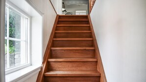 A wooden staircase with white walls and a window on the left.