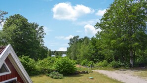 A rural property with a red building, a grassy yard, and a dirt path leading to a lake.