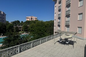 A rooftop terrace with a pool, outdoor seating, and a view of surrounding buildings and trees. - M398 - Marcelli, three-room apartment with terrace in residence with pool (Marcelli)