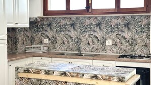 A kitchen with a patterned backsplash, a sink, a stove, and cabinets. - SE106 - Senigallia, new two-room apartment facing the sea (Cesano)