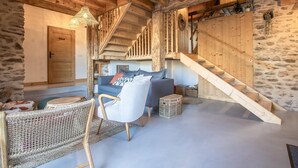 Un intérieur rustique en bois, avec un escalier, un canapé et un fauteuil en osier.