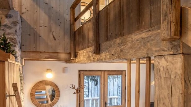 Un intérieur en bois avec un banc, un miroir rond et une porte.
