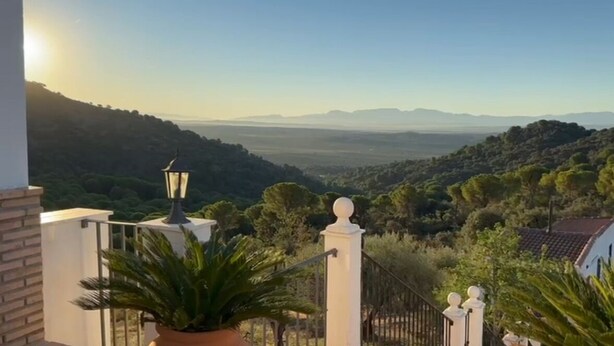 A balcony with a view of a hilly landscape, a potted plant, and a lamp post. - Casa Sierra Morena. Lince (AN)