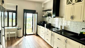 A modern kitchen with white cabinets, a black countertop, and a view through the door to a balcony. - Casa Sierra Morena. Lince (AN)