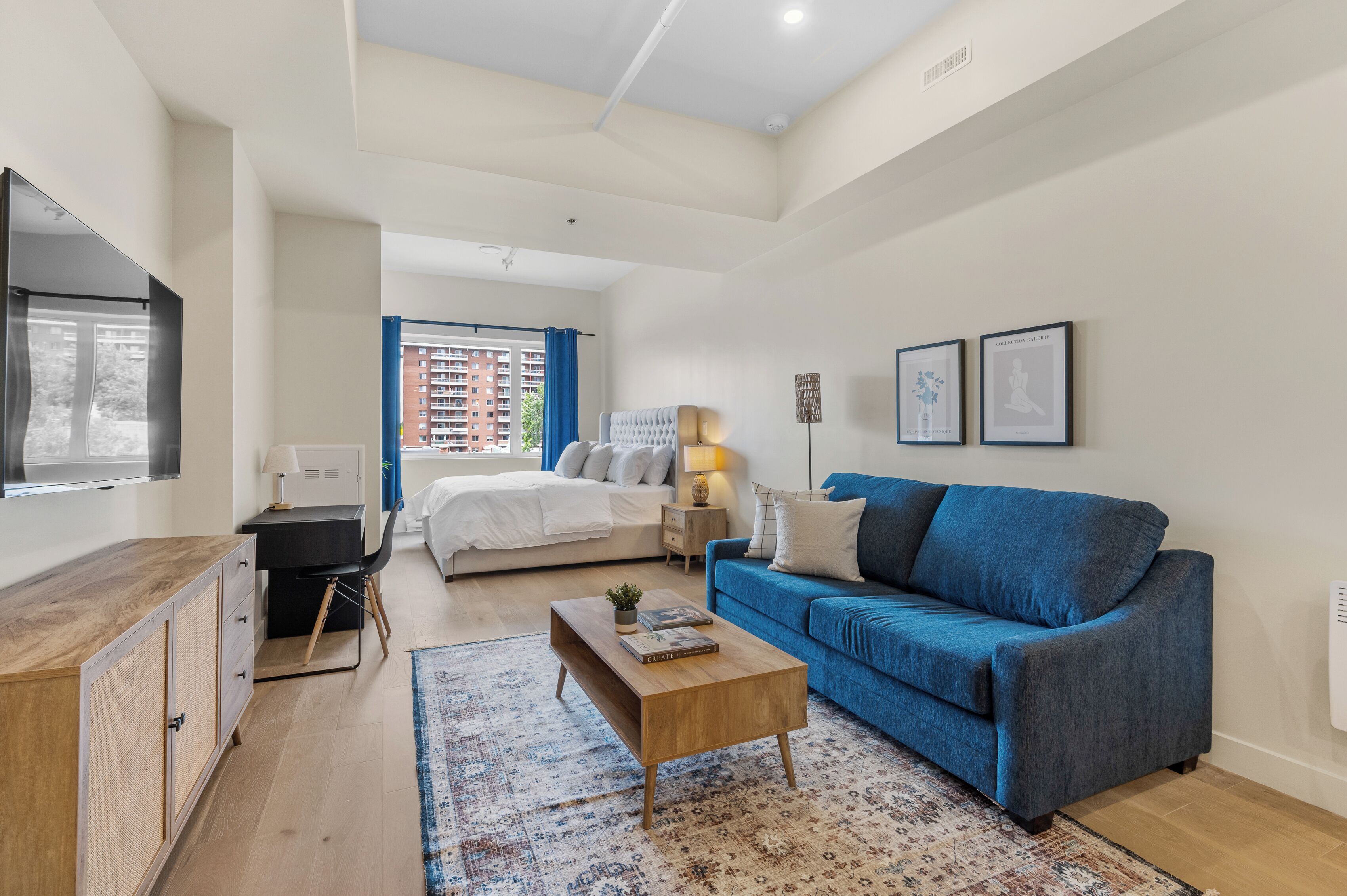 Quarto moderno com cama, sofá azul, mesa de centro de madeira e escrivaninha.