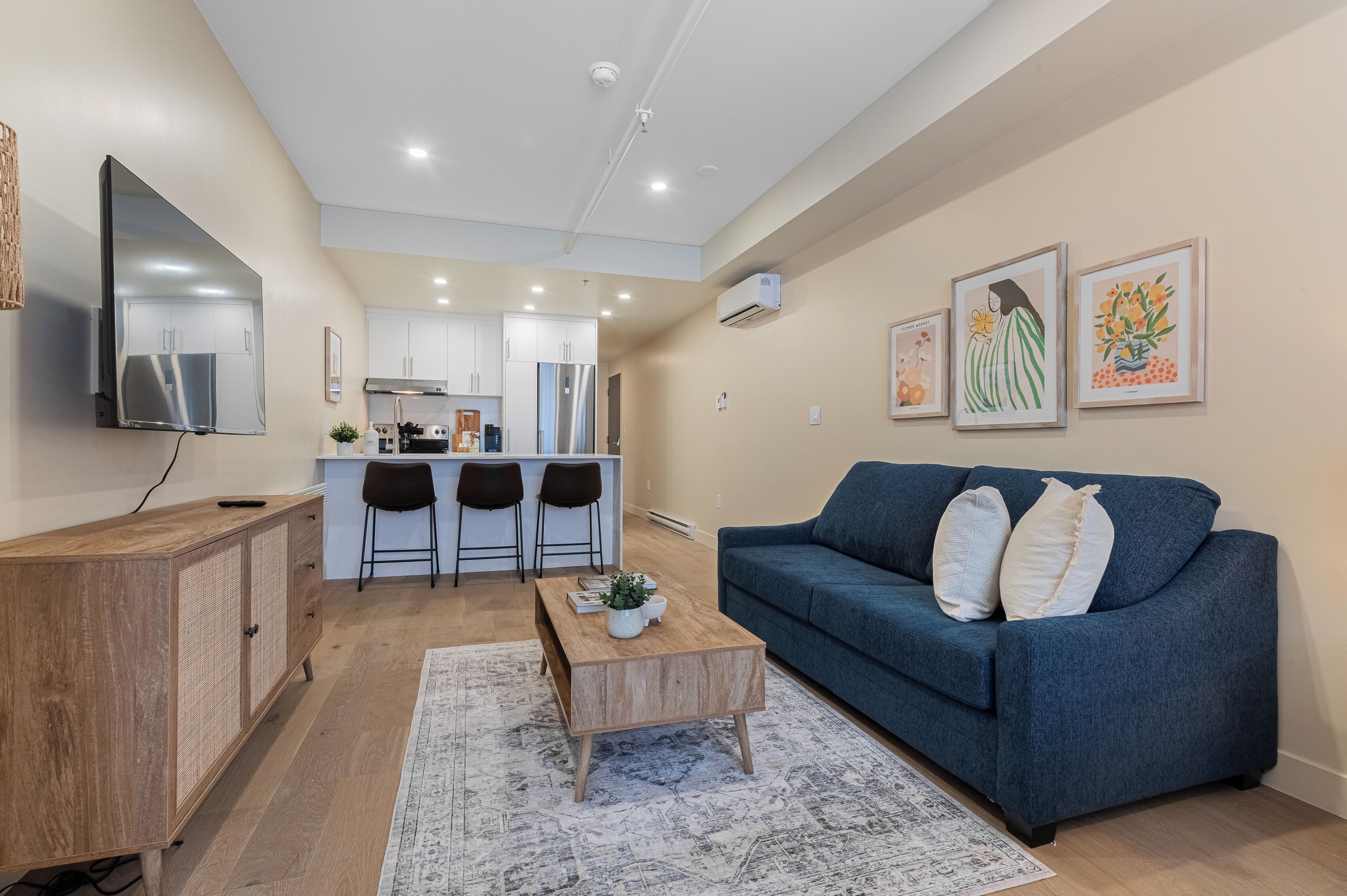 A modern living room with a blue sofa, wooden coffee table, and a TV on a wooden cabinet.