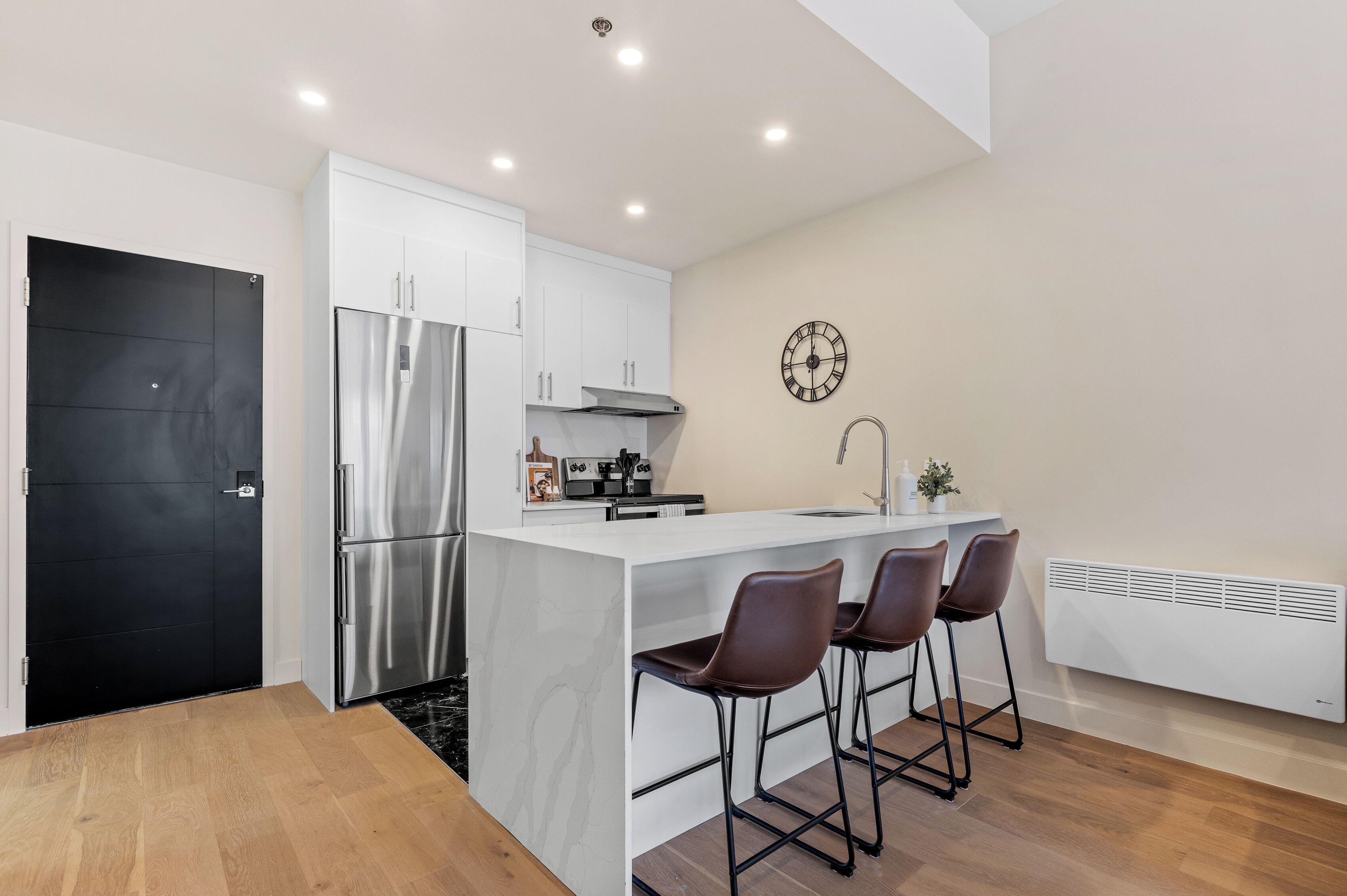 Una cocina moderna con una isla central, electrodomésticos de acero inoxidable y una puerta negra.