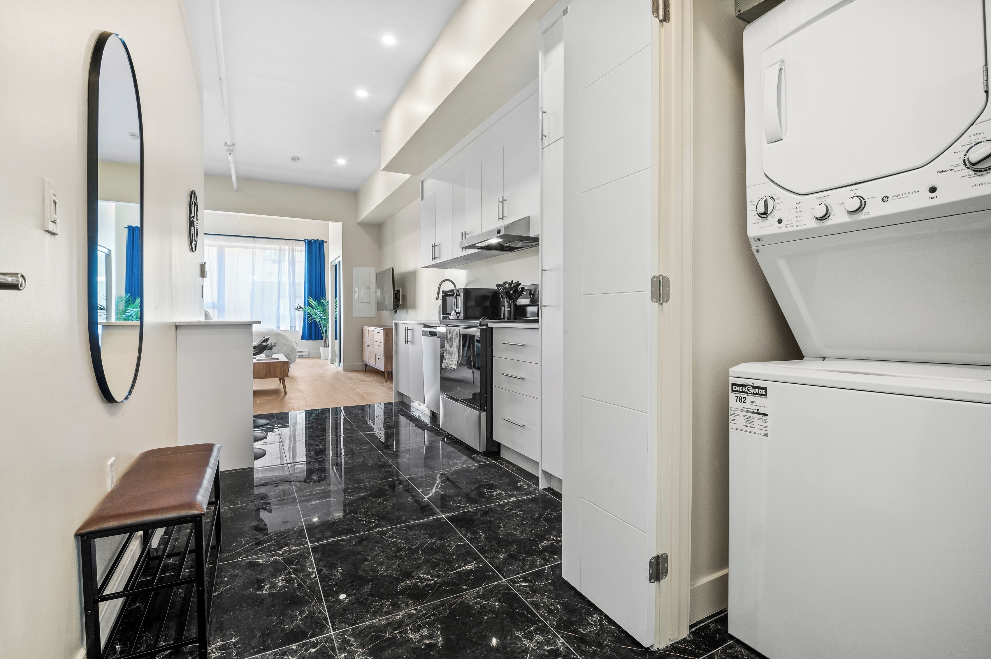 Une cuisine moderne avec des meubles blancs, un four encastré et un lave-linge.