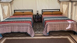 Una carpa con dos camas, cada una con ropa de cama estampada y almohadas marrones.