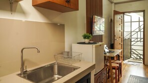 A kitchen with a stainless steel sink, wooden cabinets, a small table with chairs, and a potted plant.