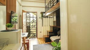 A compact living space with a kitchenette, a dining area, and a staircase leading to an upper level.