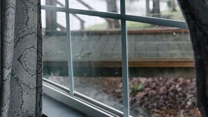 Una ventana con vista a una terraza de madera y árboles.