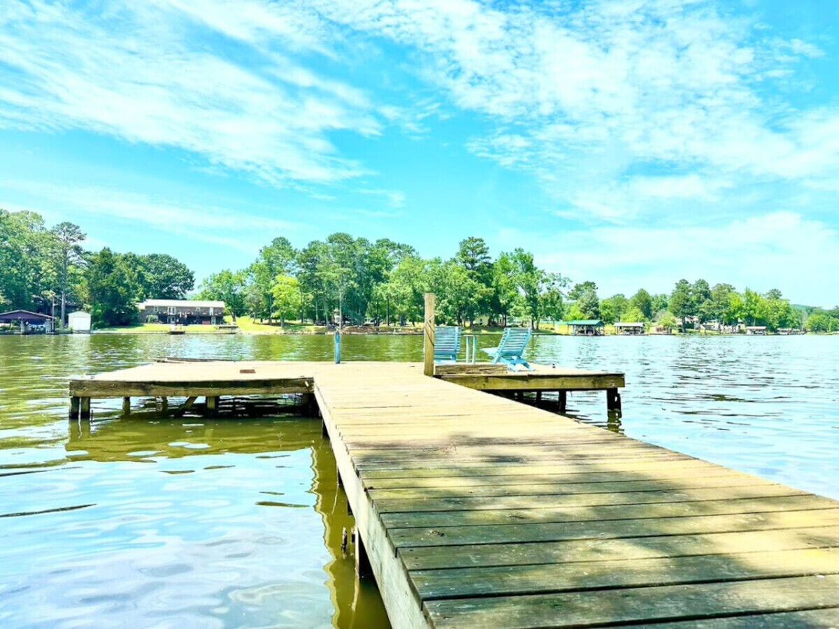 A wooden dock extending into a calm lake with a clear sky above.