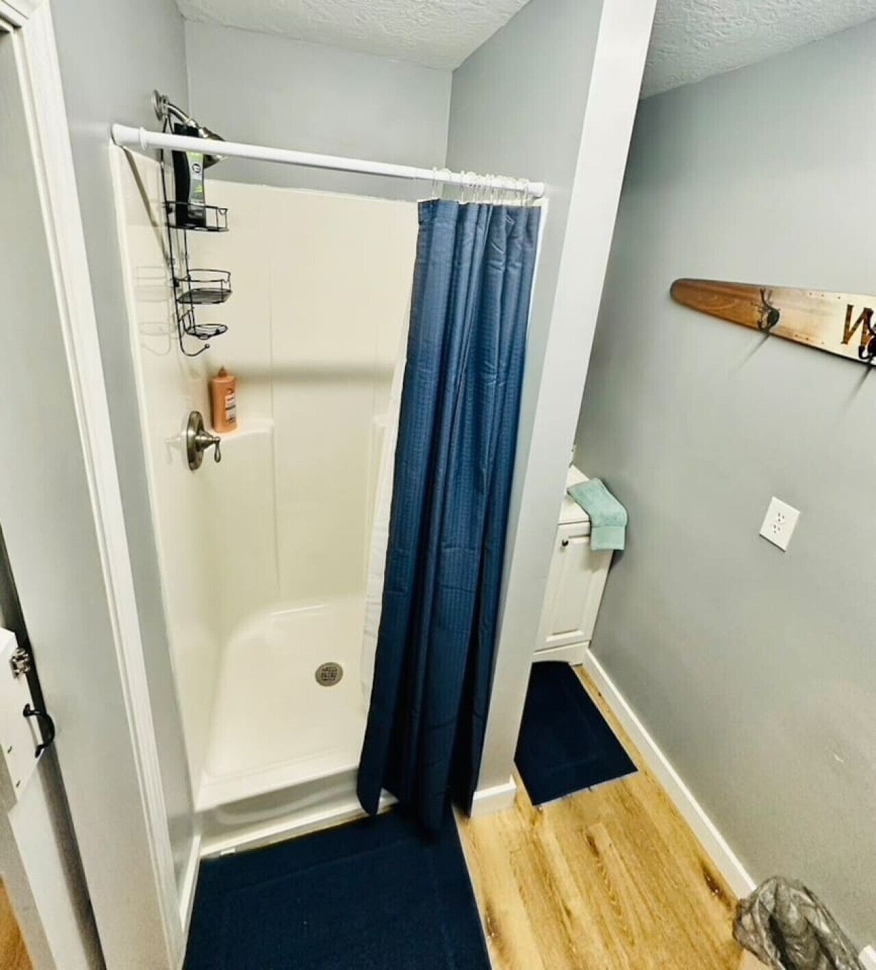 Ein Badezimmer mit Dusche, Handtuchhalter und einer Holzdekoration an der Wand.