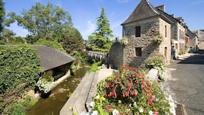 A stone building with a steep roof, a small garden with flowers, and a narrow water channel. - Villa Kercy - Plestan (PLESTAN)