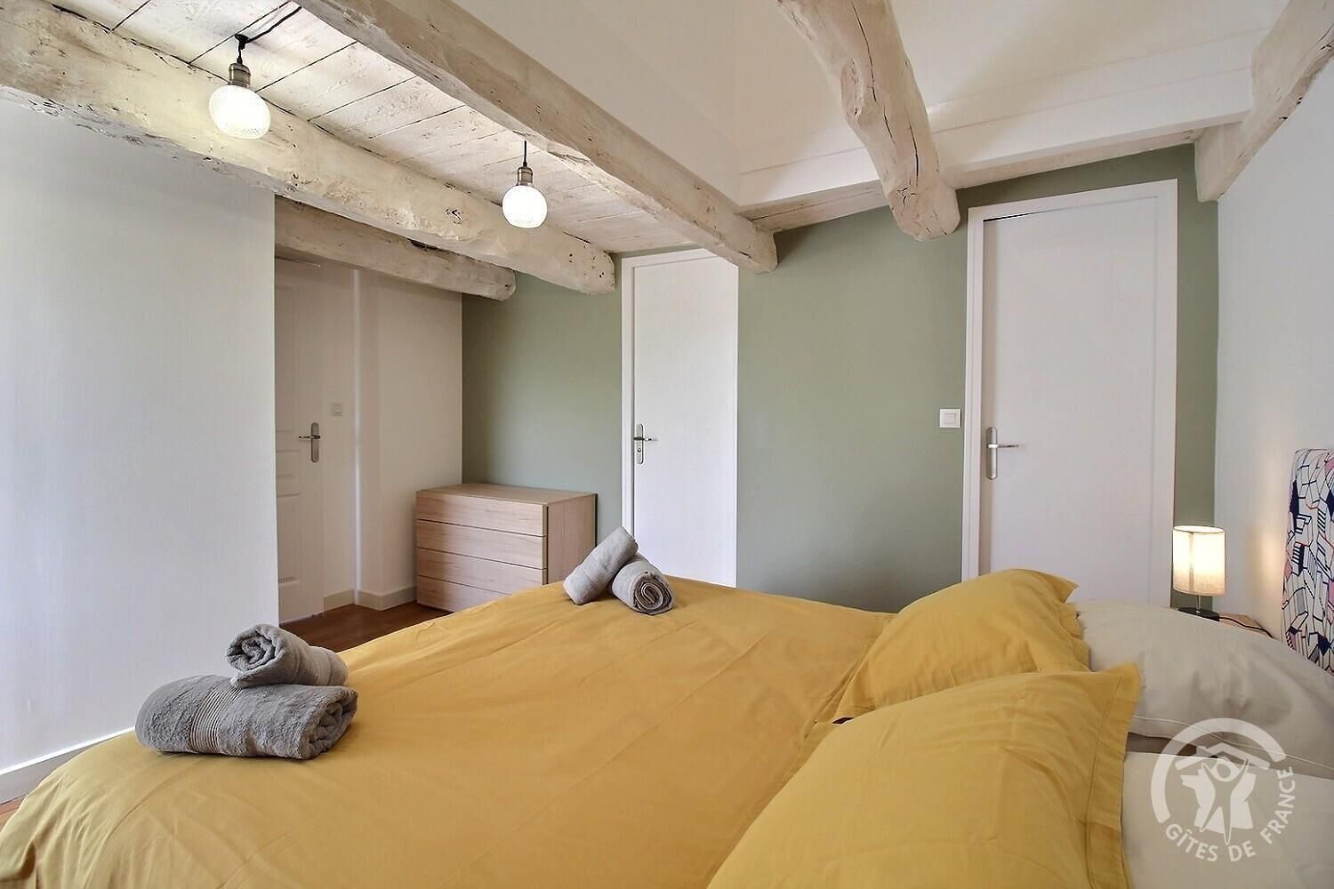 A bedroom with a bed, a nightstand, a dresser, and a door.