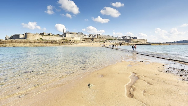 A coastal beach with clear waters, a pier, and historic buildings in the background. - Villa Kercy - Plestan (PLESTAN)