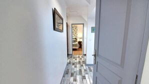 Un pasillo con piso a cuadros que conduce a una habitación con cama y mesita de noche.