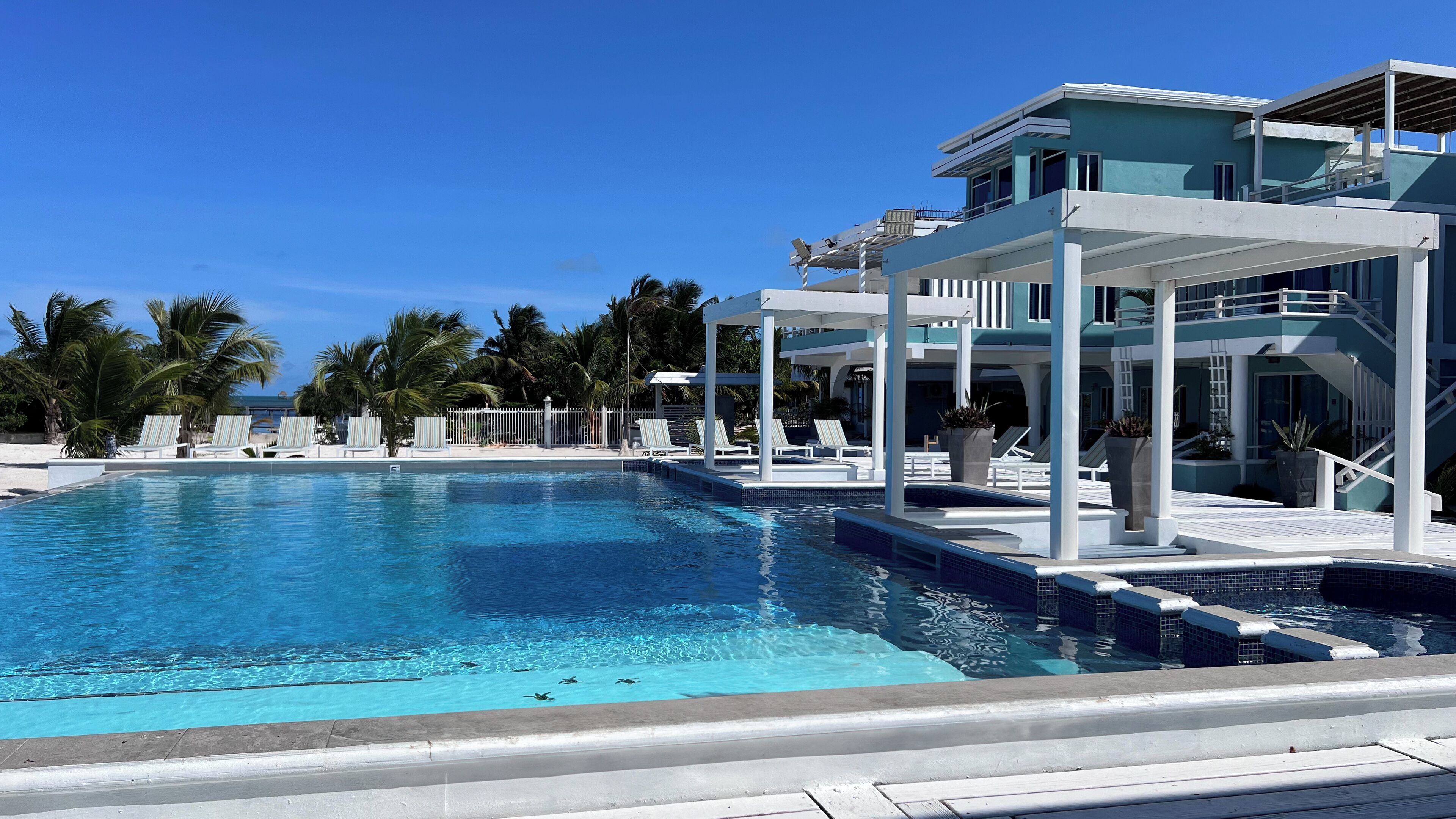 A swimming pool with lounge chairs and a multi-level building with a balcony.