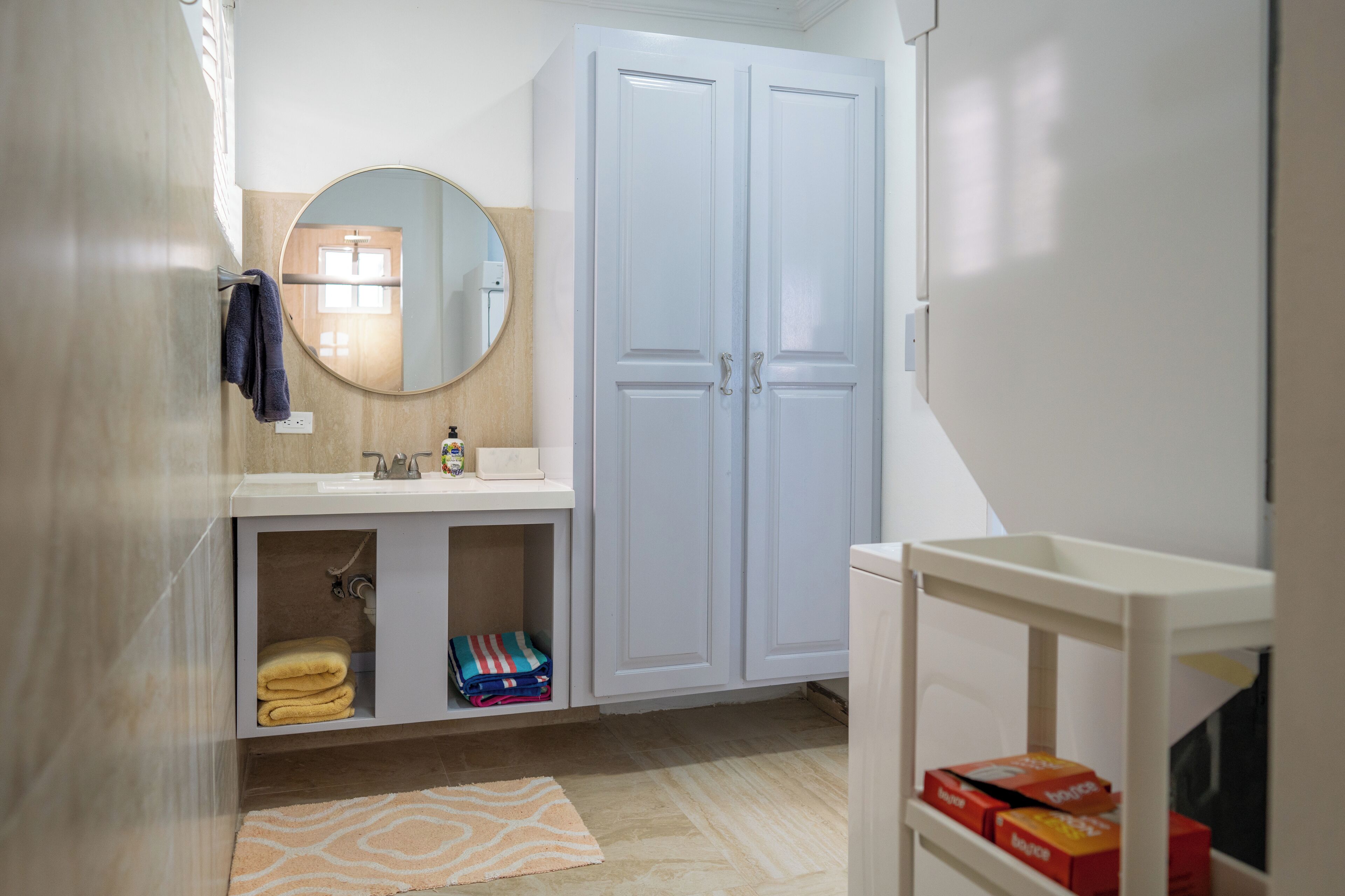 A bathroom with a sink, mirror, and two cabinets.