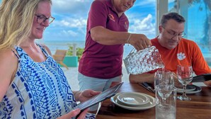 A dining table with a clear view of the sky and ocean through large windows. - Island Magic Villas (Caye Caulker)