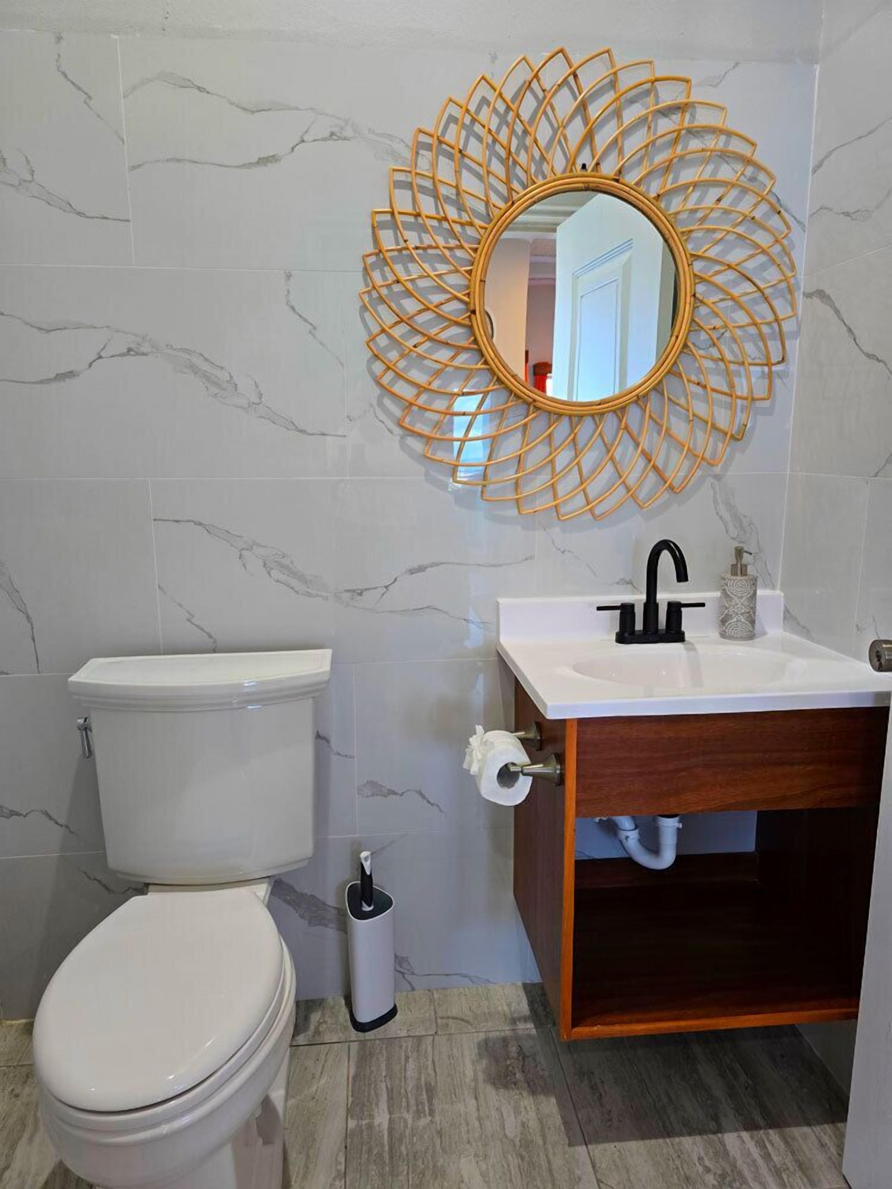 A bathroom with a toilet, sink, and mirror.