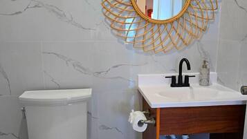 A bathroom with a toilet, sink, and mirror.