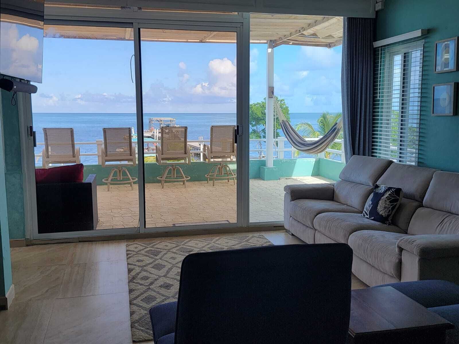 A room with a sliding glass door leading to a balcony with beach chairs and a hammock.