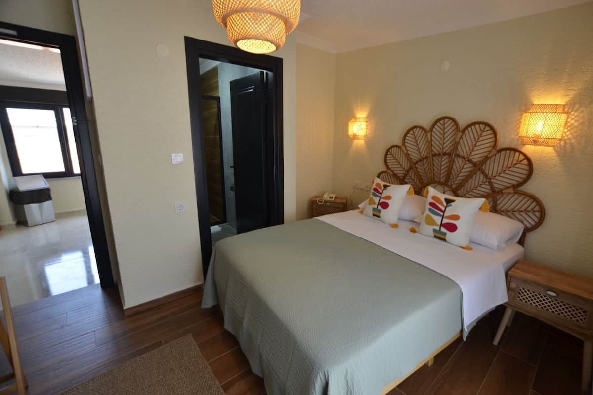 A bedroom with a large bed, a wooden headboard, bedside lamps, and a door leading to another room.