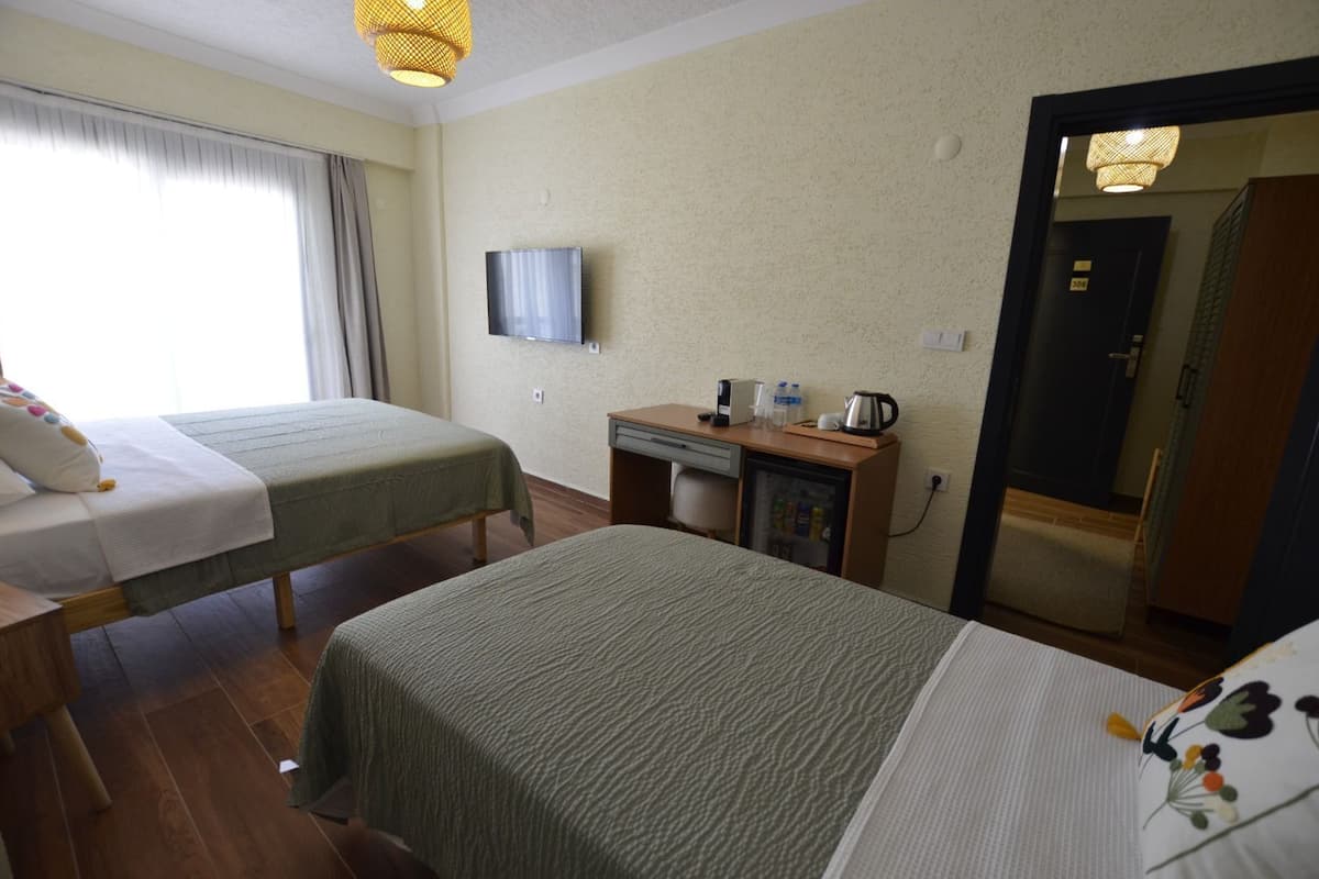 A hotel room with two beds, a desk with a refrigerator, a television, and a door to a bathroom.