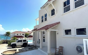A two-story building with a covered porch, a pool, and a white SUV parked in front.