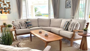 Uma sala de estar moderna com um sofá modular bege, uma mesa de centro de madeira e uma pequena mesa lateral com uma planta.