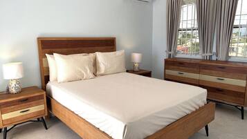 Un dormitorio con cama de madera, mesitas de noche, cómoda y ventana con cortinas.