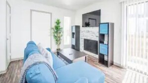 A modern living room with a blue sofa, a coffee table, and a TV.