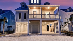 A two-story beachfront house with a covered front porch and a balcony.