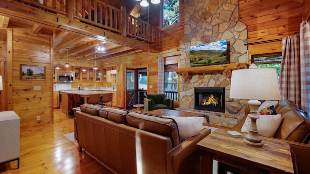 Un interior de cabaña espacioso con chimenea de piedra, muebles de madera y una zona de cocina.