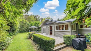 A small, single-story house with a deck, surrounded by lush greenery. - Fisherman’s retreat in Turangi (Turangi)