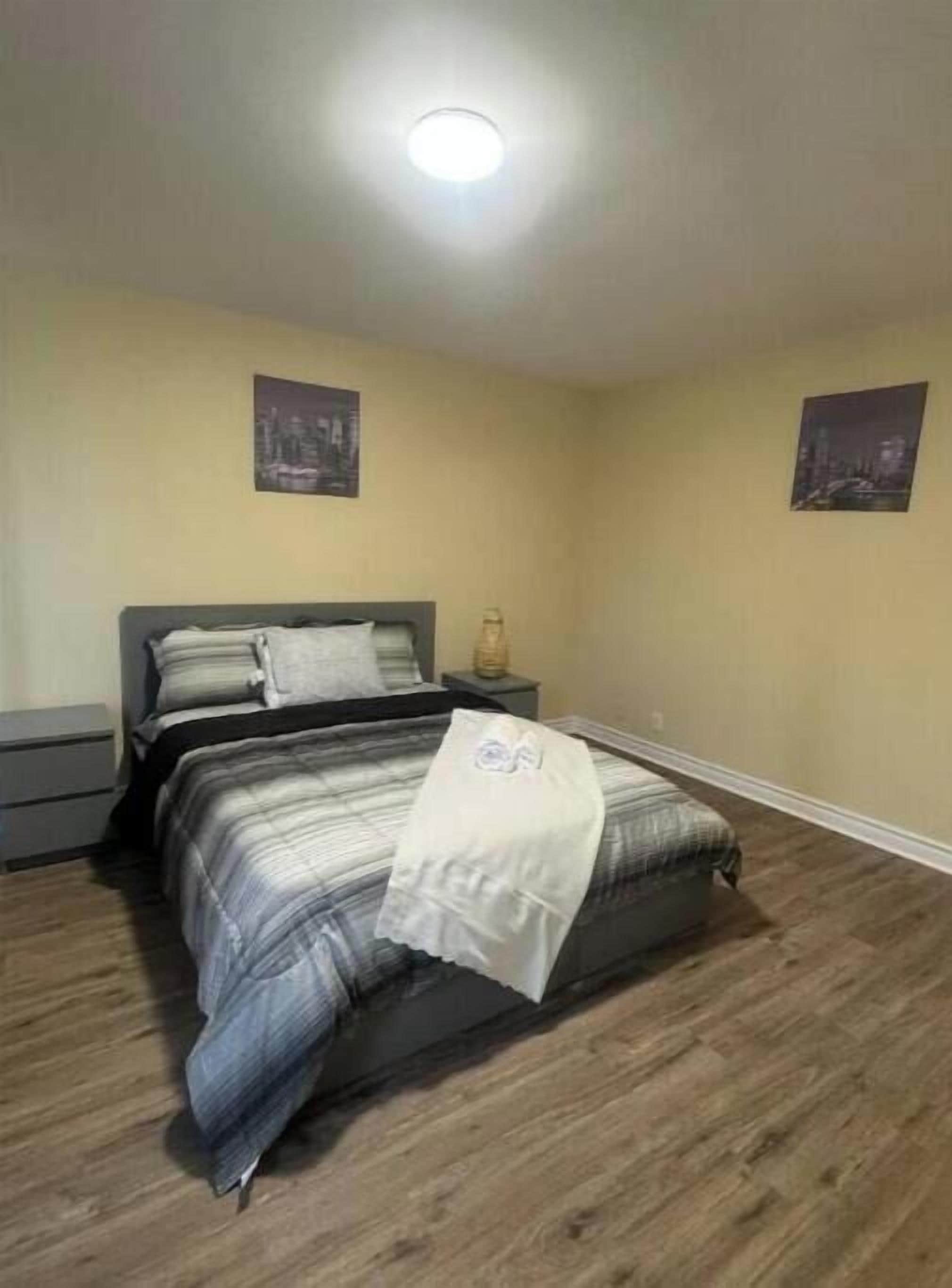 A bedroom with a bed, nightstands, and two wall-mounted pictures.