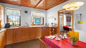 Een keuken met houten kasten, een rode tafel en een eethoek met stoelen.