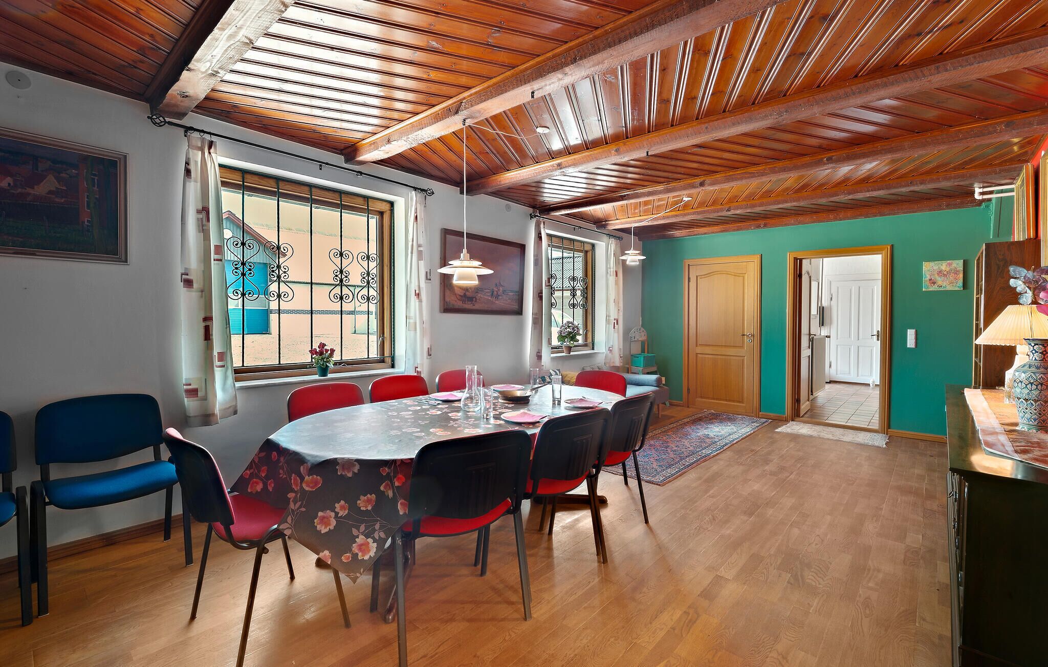 A dining area with a wooden ceiling, a large window with decorative iron bars, and a table set for four.