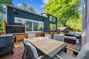 Ein modernes Haus mit Terrasse, Gartenmöbeln und Grill.